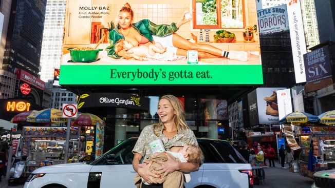 Femme allaitant un bébé devant un panneau publicitaire