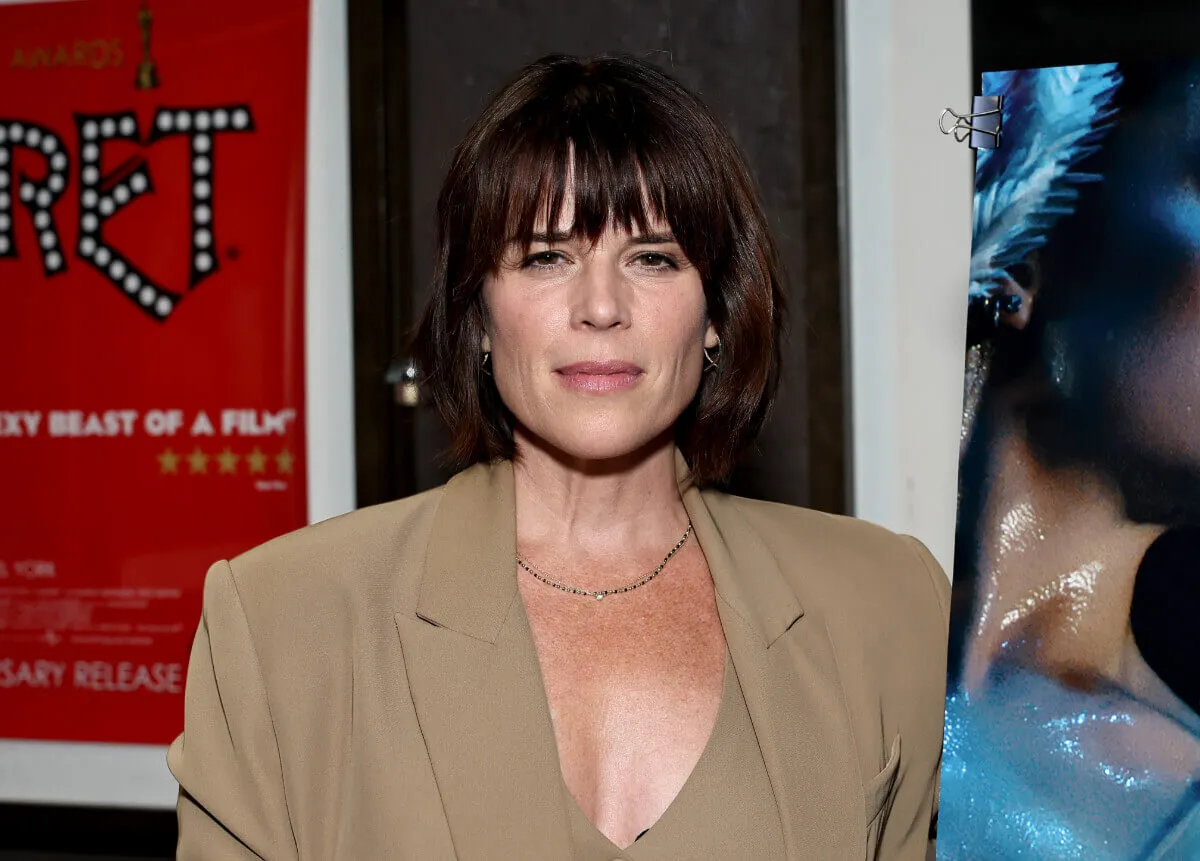 Neve Campbell porte un blazer beige et une chemise assortie.