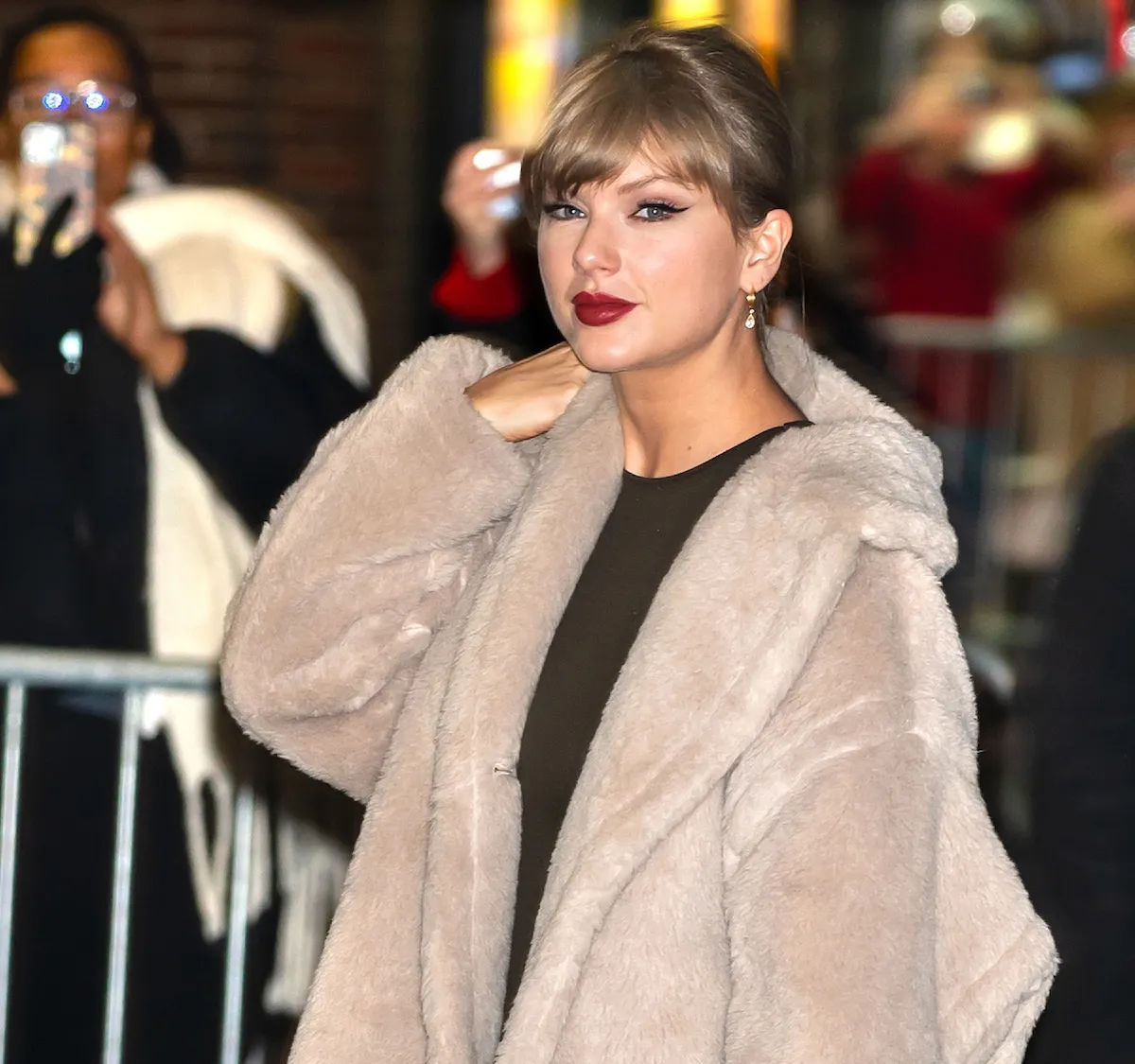Taylor Swift avec une frange, un eye-liner œil de chat et un manteau en fausse fourrure