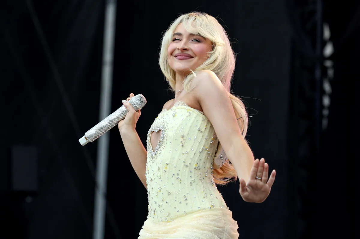 Sabrina Carpenter porte un body jaune et tient un microphone.