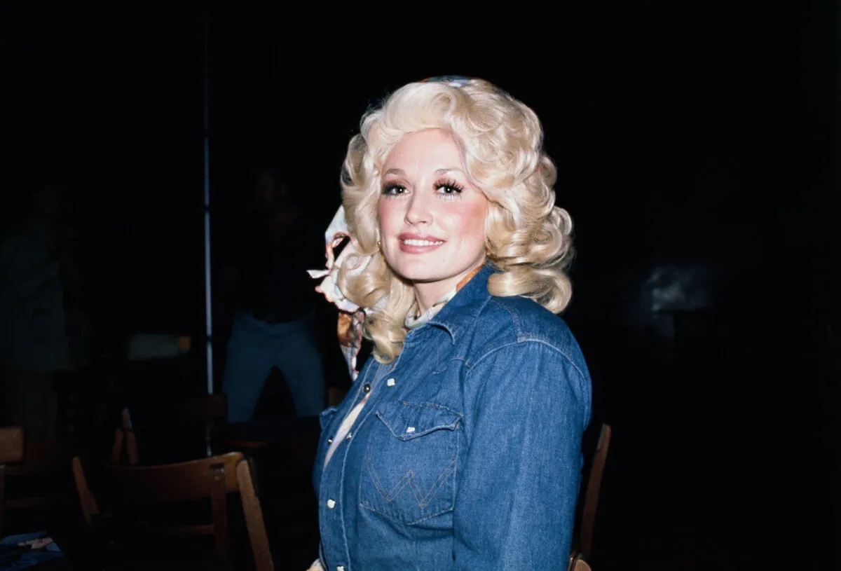 Dolly Parton porte une chemise en jean et un foulard dans les cheveux.