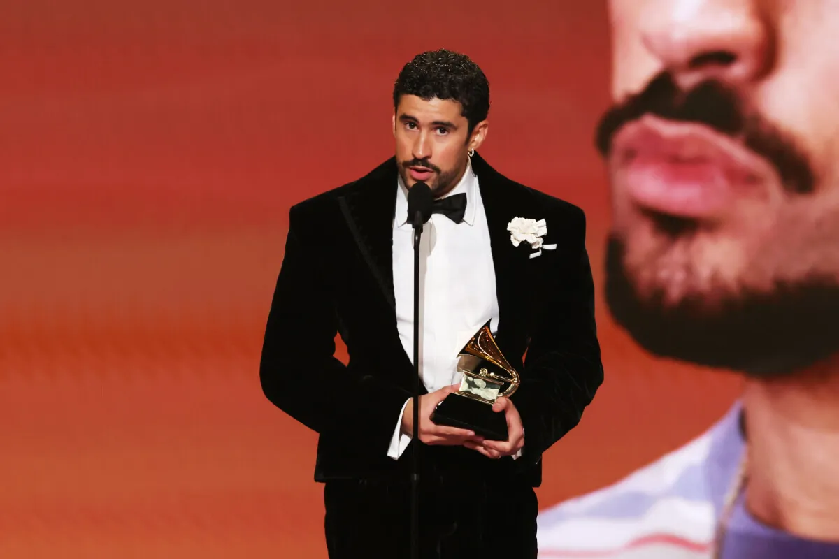 Bad Bunny porte un smoking et détient un Grammy Award. Il parle dans un microphone.