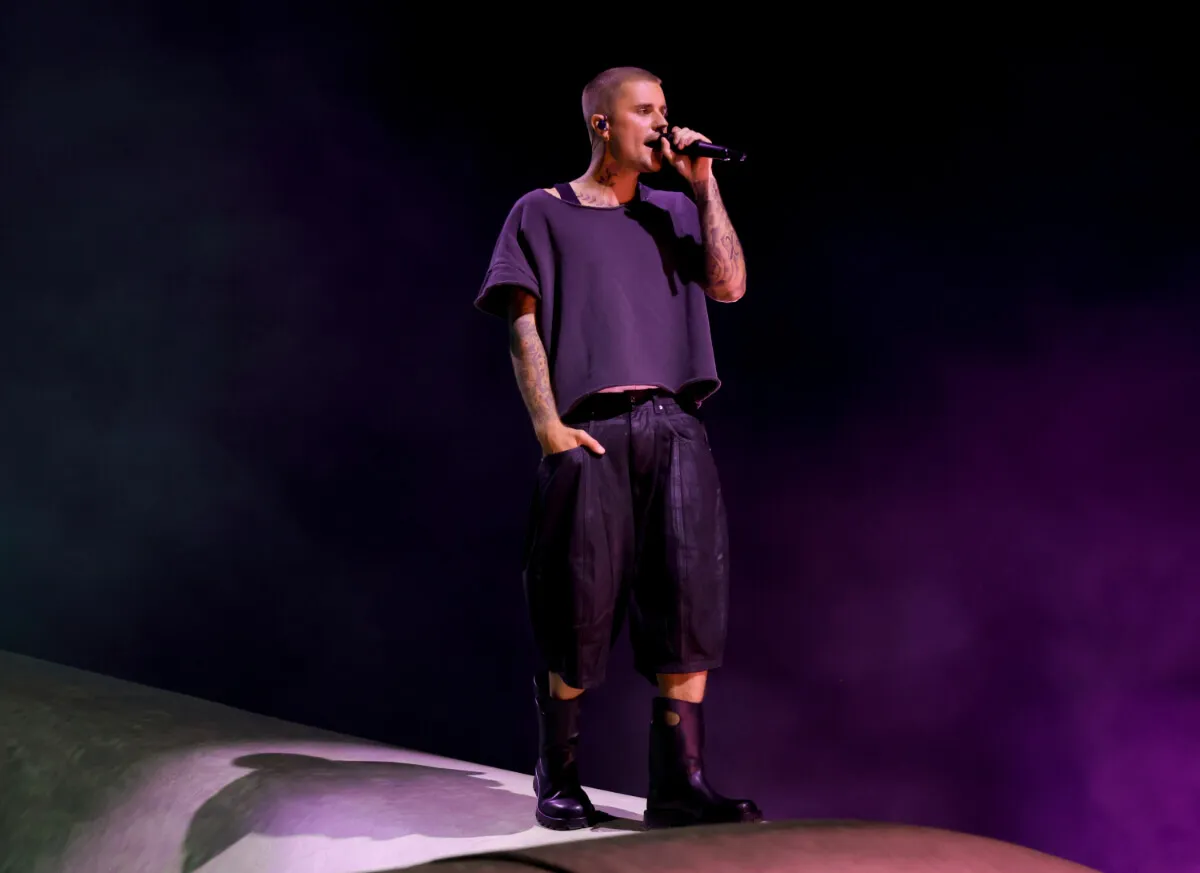 Justin Bieber porte une chemise et un short noirs et chante dans un micro à Coachella.